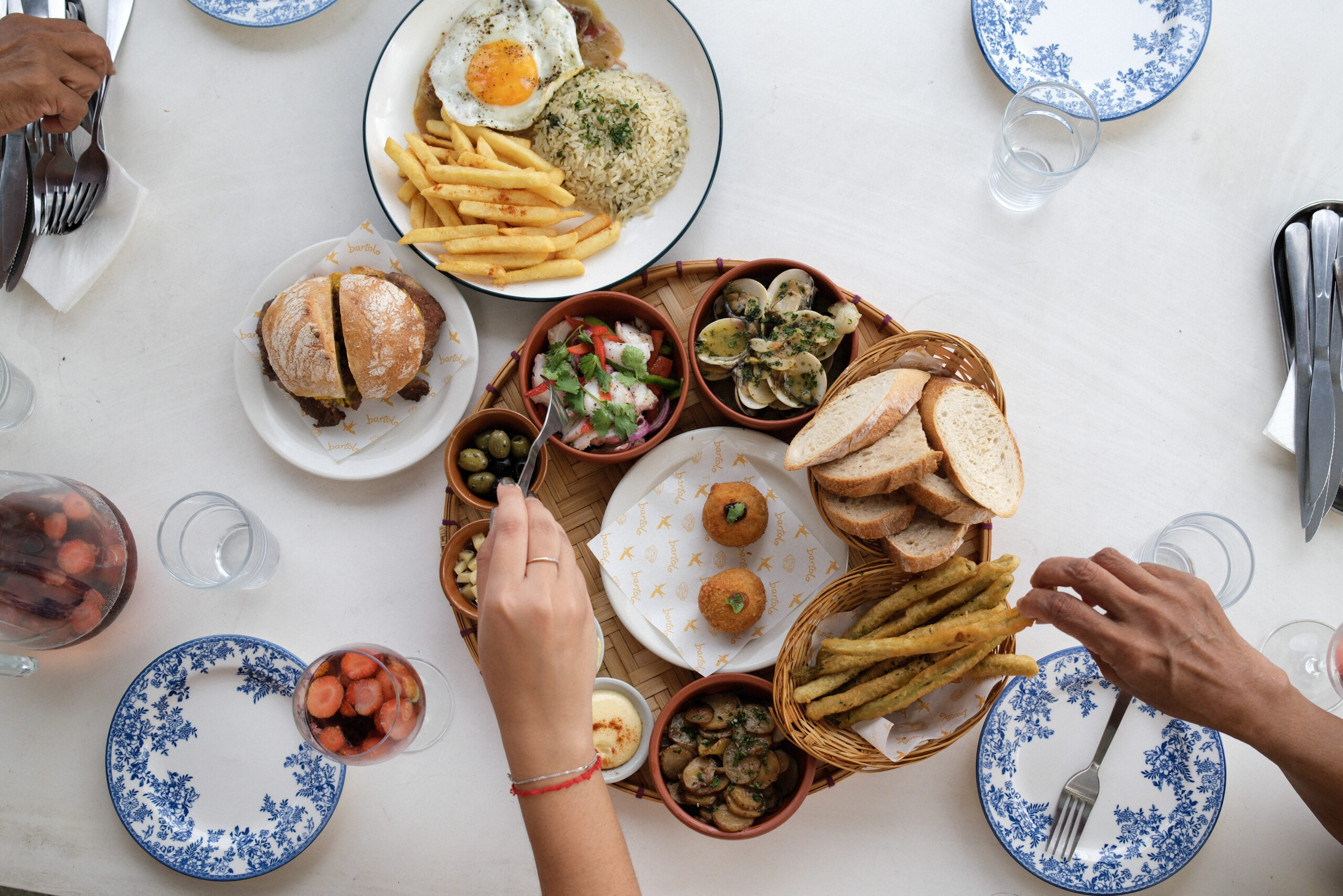Bartolo catering — shared Portuguese petiscos table with friends gathering, top-down view