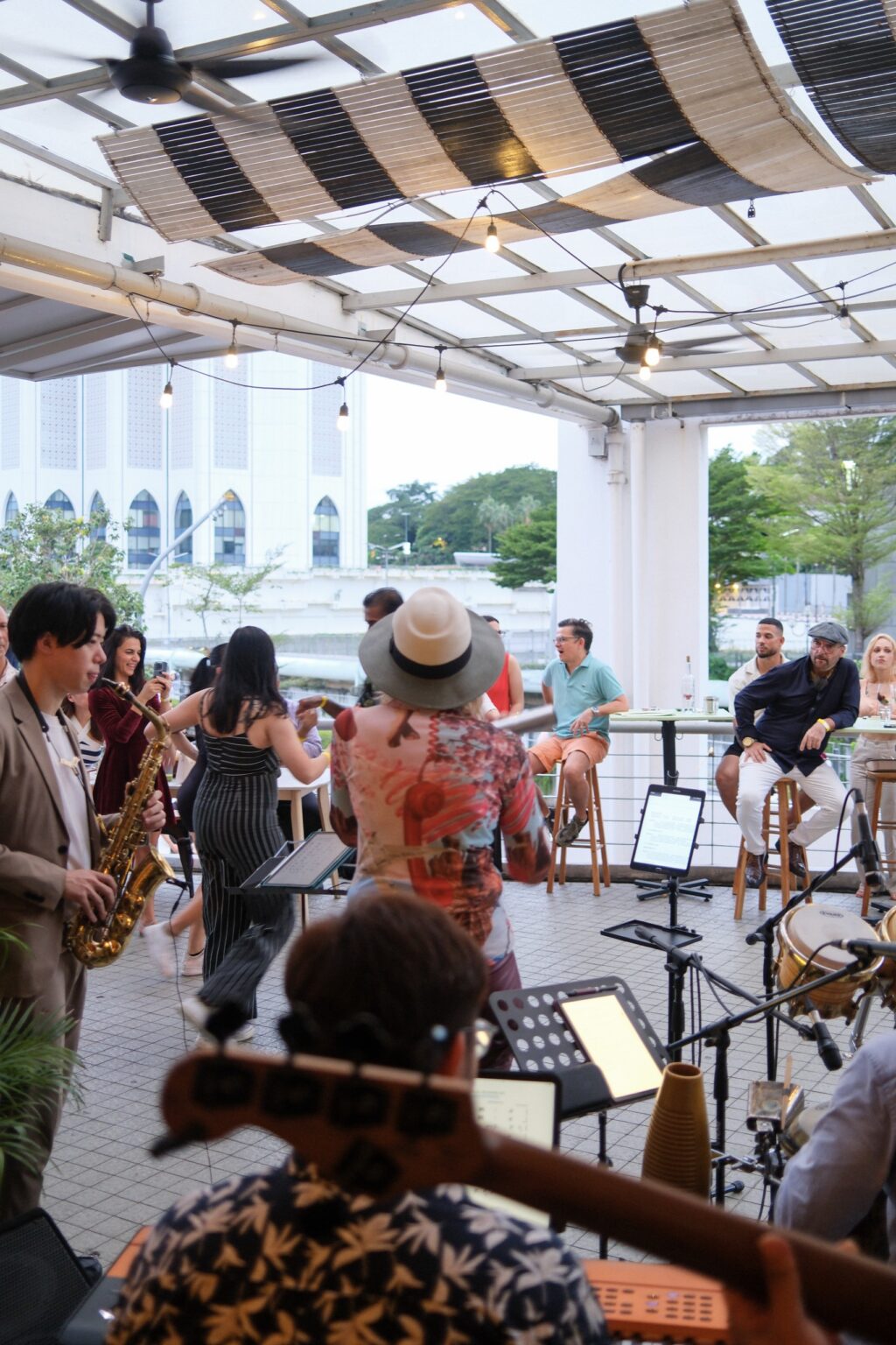 Saxophonist mid-solo with crowd on the Bartolo terrace, city skyline behind